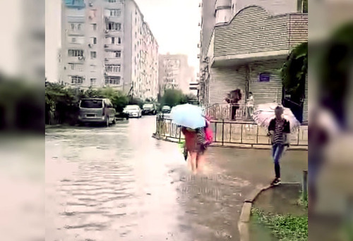 A resident of Krasnodar walks along a flooded street. Image made from video posted at: https://vk.com/wall-33025155_10315557